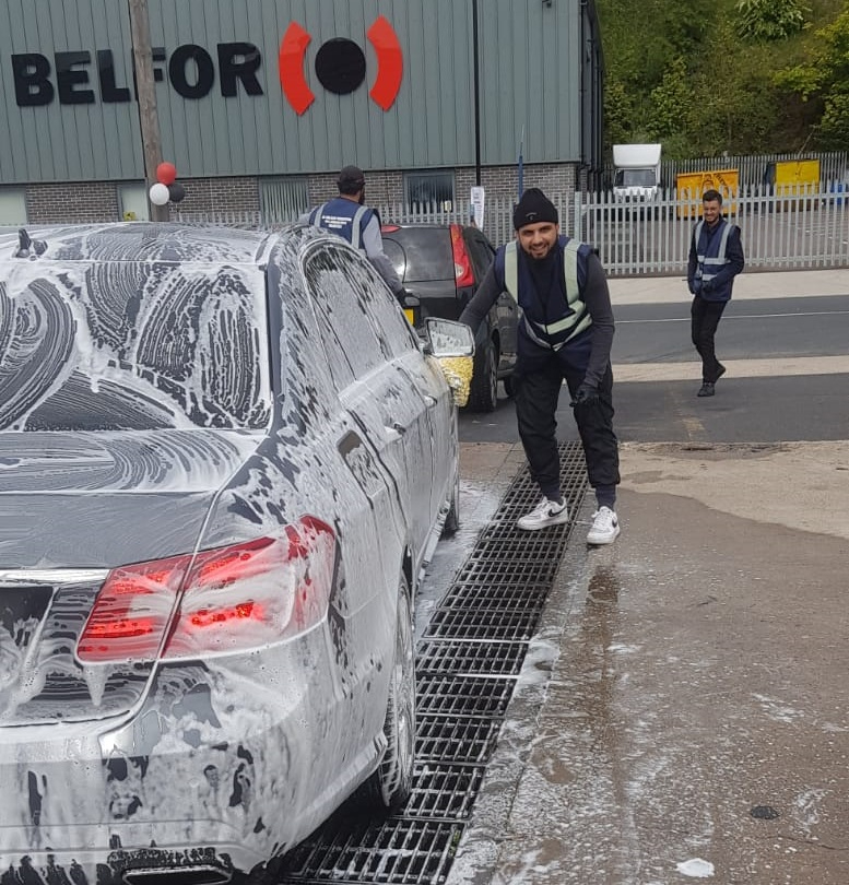 A volunteer washing a car as part of a charity car wash