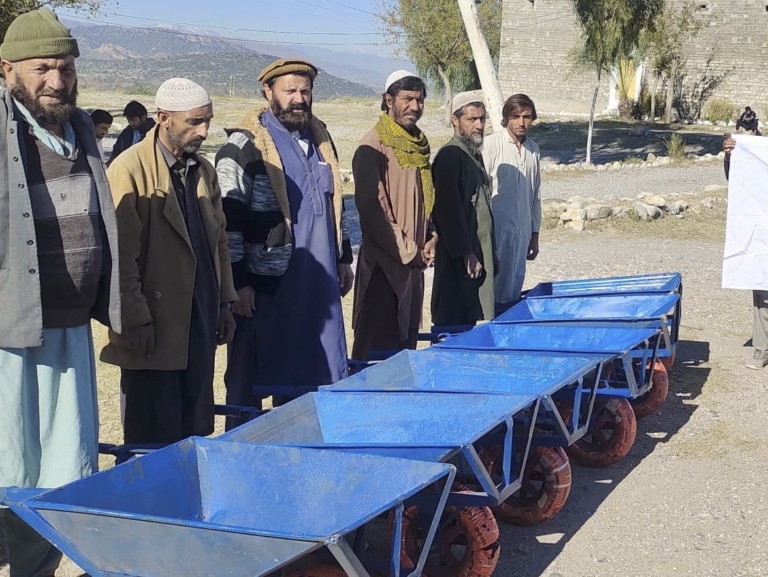 A line of men with wheelbarrows in Pakistan to help them earn a livelihood