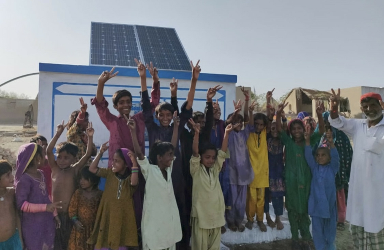 Kids cheering in front of a solar-powered water well in Pakistan