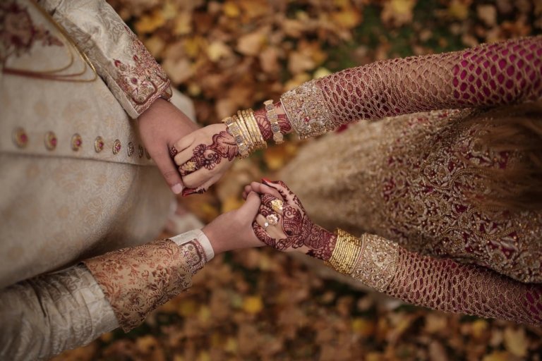 A Pakistani couple holding hands in traditional wedding outfits sponsored by Muazzam Foundation's wedding sponsorship programme